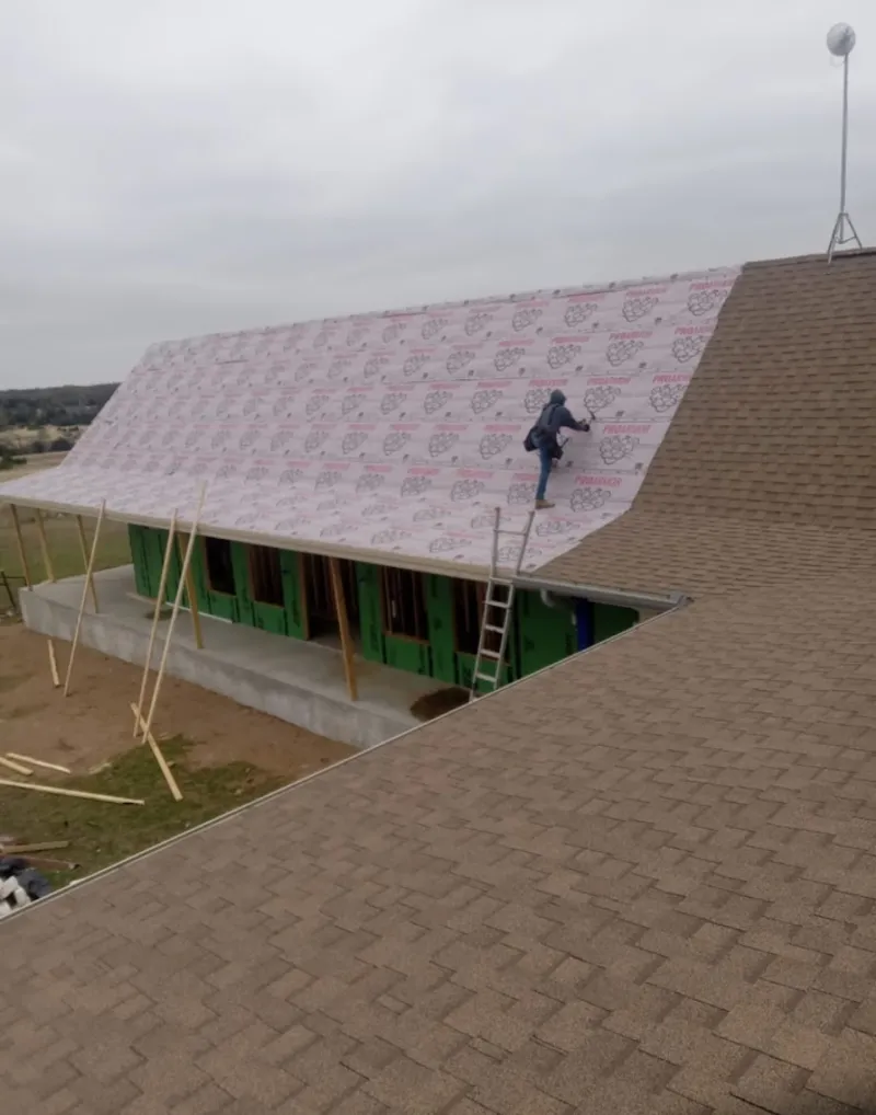 Worker preparing underlayment for a metal roof installation in East Hills